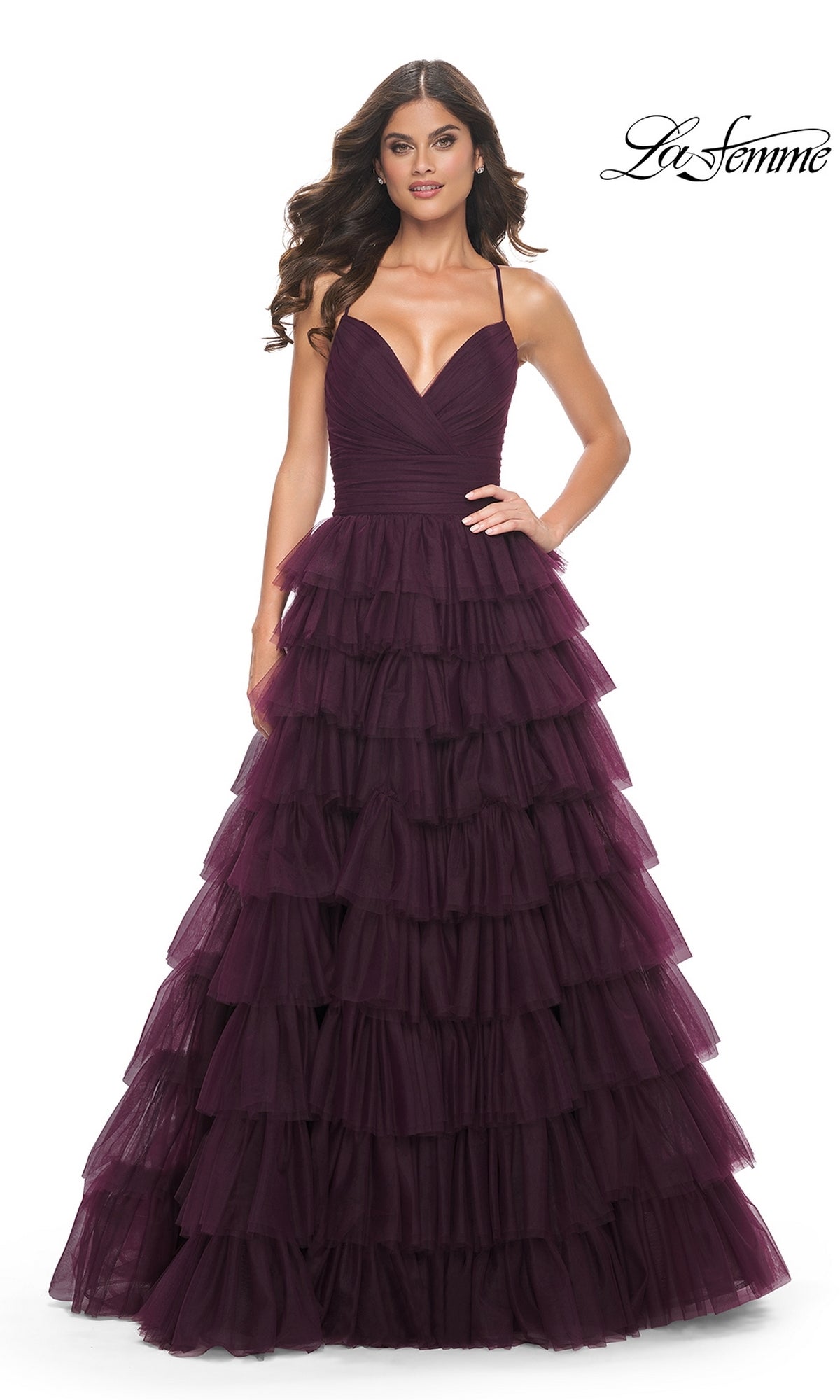 A woman models the La Femme Lace-Up Long Tiered Prom Dress 32086 in deep purple, featuring spaghetti straps, a fitted bodice, and a voluminous ruffled skirt, standing against a white background.